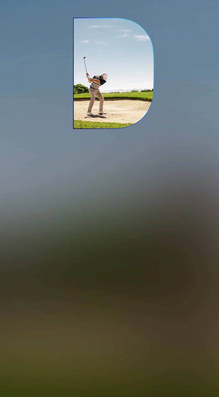Golfer swinging a club from a sand trap during a sunny day on a professional golf course.
