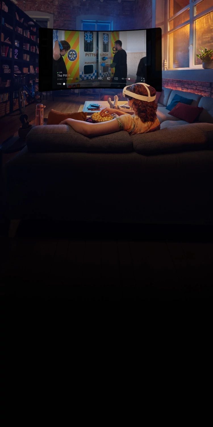 Person wearing a Meta Quest headset lounging on a couch while watching DIRECTV on a large curved virtual screen in a living room.