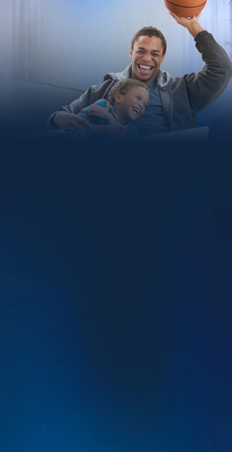 Smiling father and son relaxing together at home, with the father holding a basketball.