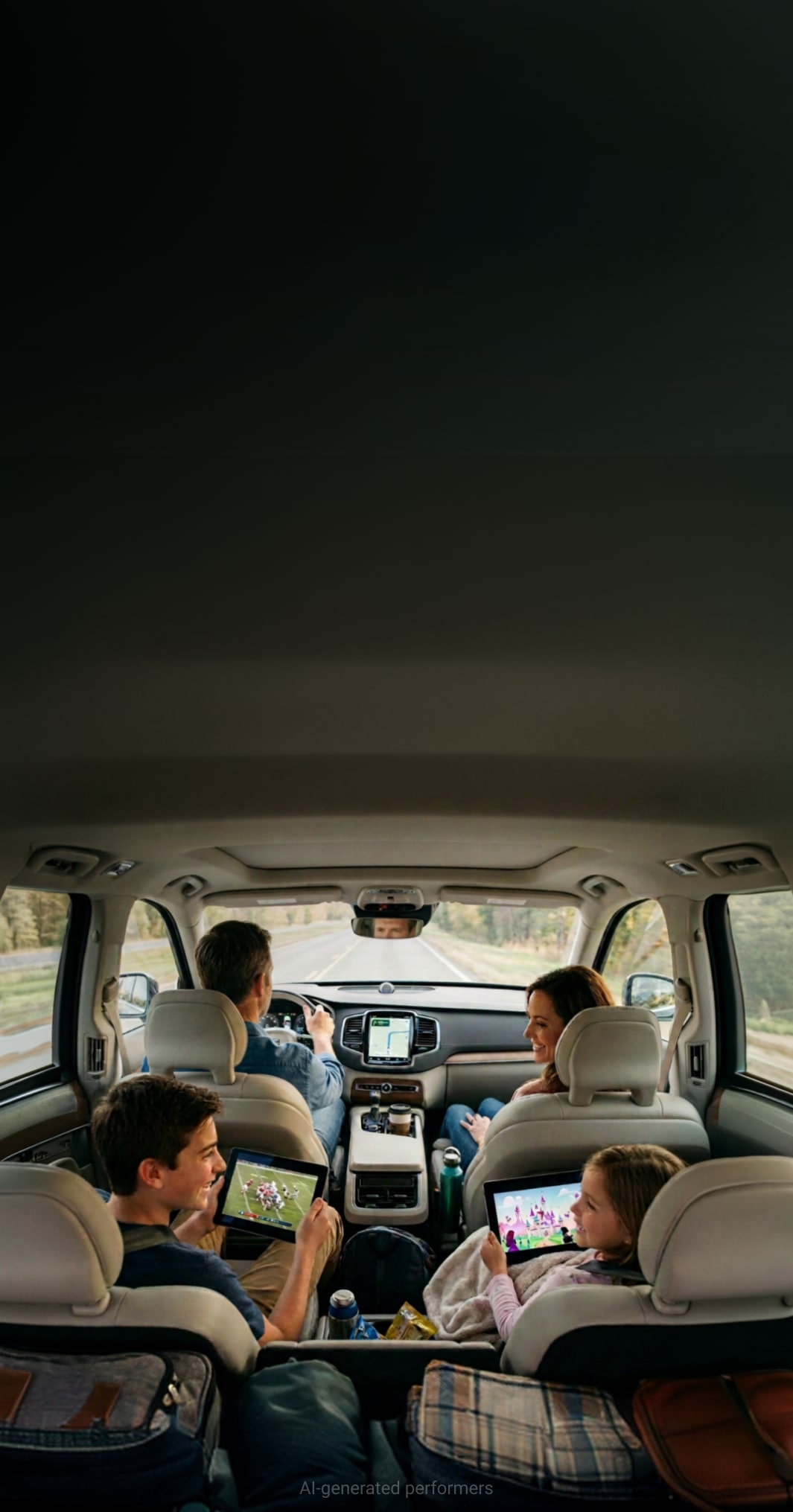 A family in a car watching separate programs on two tablets in the back seat while the parents sit up front.