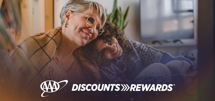 Smiling woman relaxing on a couch with a child, with the AAA Discounts & Rewards logo overlayed on a warm, cozy background.