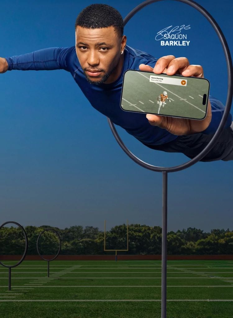 Saquon Barkley jumping through a training hoop on a football field while holding a phone with notifications from a Texas football game