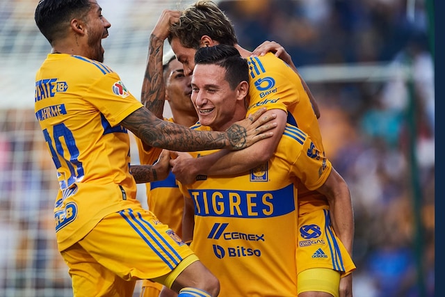 Four professional soccer players embrace after a victory.